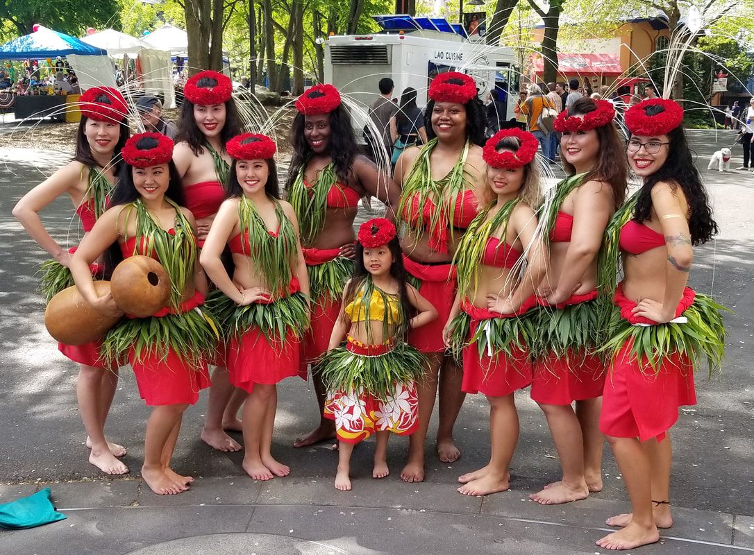 Huraiti Mana pose at the Seattle Center in their ori Tahiti regalia of red pareu, red carnation lei po'o (head adornment), ni'au, and ti-leaf hip.