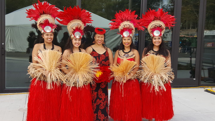 Photo of Huraiti Mana dressed in 'ahu no ka hula (hula regalia, center) and 'ahu no te 'Ori Tahiti (Tahitian dance regalia), ready for their performance.